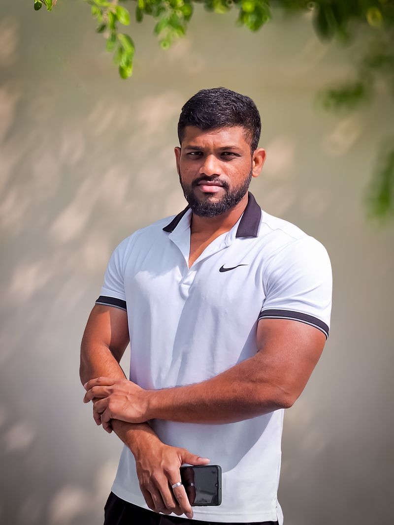 Representative portrait — A muscular man standing confidently in a white polo shirt outdoors, showcasing fitness and strength.
