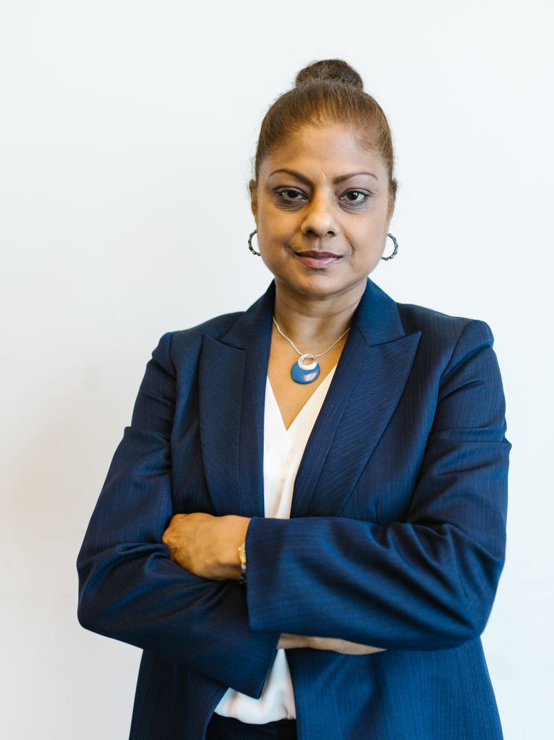 Representative portrait — Confident woman in a suit with arms crossed, expressing leadership and professionalism in an office setting.